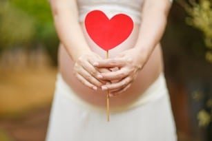 pregnant woman holding a decorative red heart