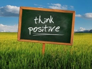 think positive written on chalkboard planted in field